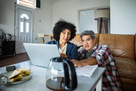 Mature couple managing finances on laptop at home