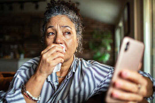 Upset senior woman crying during video call at home