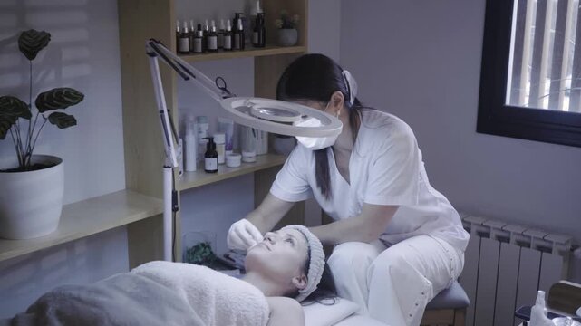 Esthetician gently cleansing client skin during calm facial treatment