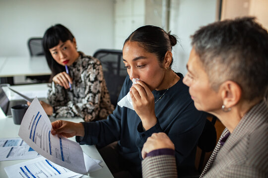 Colleagues consoling crying coworker during office meeting