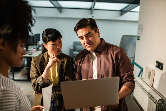 Coworkers collaborating on laptop in modern office