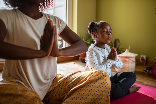 Parent and child meditating on yoga mat at home
