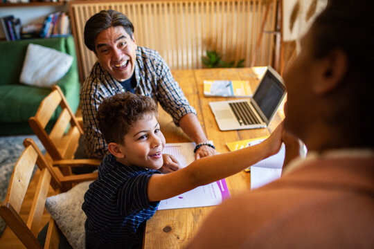 Parents helping son with homework at home dining table
