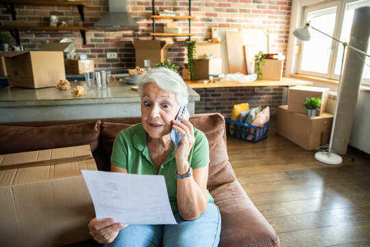 Senior woman on phone reading bill in new home