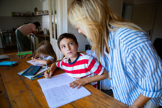 Mother helping son with math homework at kitchen table
