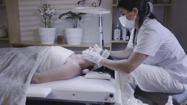 Gloved esthetician massaging client face during relaxing skincare session