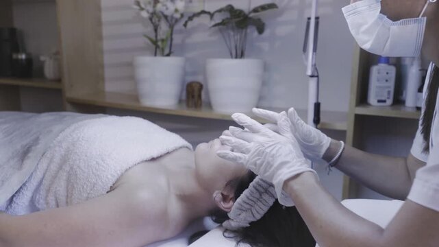Focused esthetician cleansing client face during soothing spa treatment
