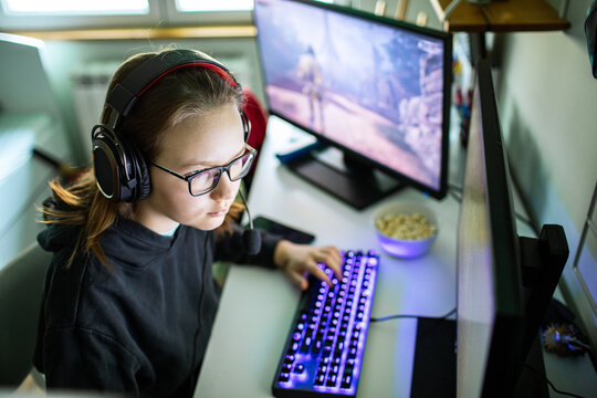 Teen gamer wearing headset playing pc game at home