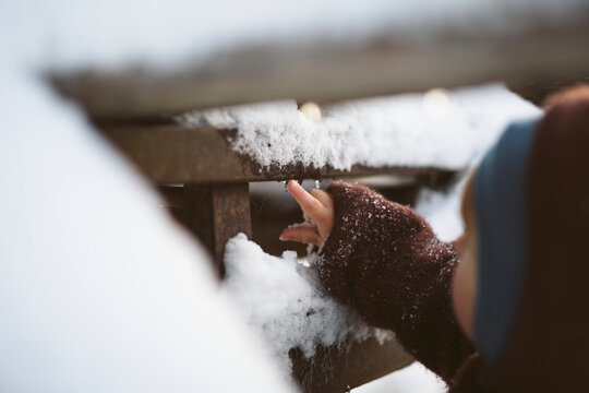 Close-up of cute baby boy touching frozen snow on wood