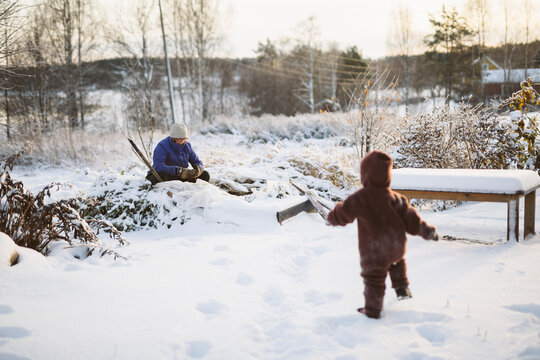 Mother and toddler son spending leisure time on snowy landscape during winter