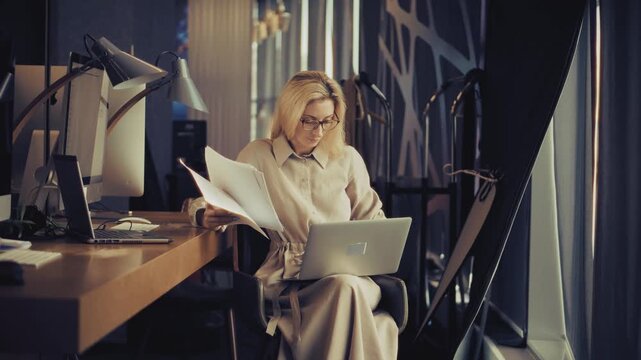 Employee Holding Laptop Computer Reading Paper Documents Sitting At Office Desk 