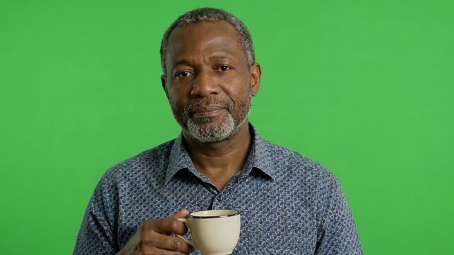 An older man sipping coffee against a vibrant green background, expressing contemplation and relaxation