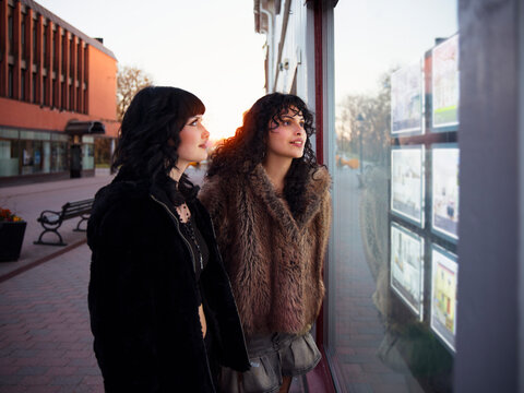 Young lesbian couple staring at store window while standing at street