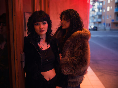 Two fashionable women standing by door in city