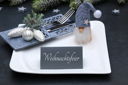 Festliche Tischdekoration f&uuml;r die Weihnachtsfeier mit Wichtel und Platzkarte auf wei&szlig;em Teller