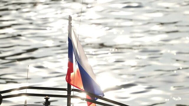 Russian flag flying from a boat, sunlight reflecting on calm water, national symbol