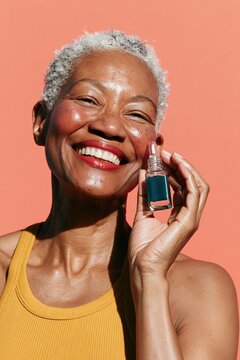 Smiling mature woman holding a facial serum bottle on coral background for skincare product banner and beauty advertising design