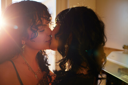 Young lesbian couple sharing romantic kiss in their apartment kitchen
