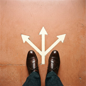 Top view of businessman shoes standing at three directional arrows on floor
