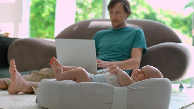 Working father on sofa as baby starts fussing in cocoon. Slow motion.