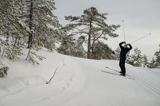 Smiling female skier holding ski poles like horns while enjoying skiing at tranquil location