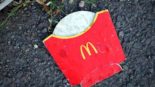 Leicester, England, UK - 17 July 2026: Discarded McDonald's French fries paper box littering asphalt ground
