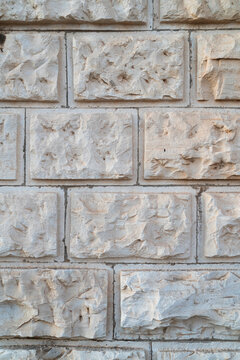 ​Vertical close up photo of ancient rusticated ashlar limestone wall masonry with chiselled stone blocks and linear joints for architectural background design.