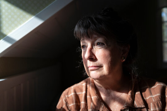 Contemplative woman looking away while sitting in bedroom