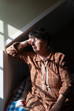 Depressed mature woman leaning on bed while sitting lonely in bedroom at home