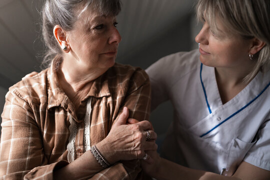 Female medical professional consoling sad woman during house call