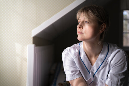 Contemplative medical professional looking away while sitting in bedroom at home