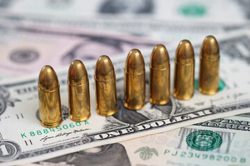 Fototapeta premium Row of ammunition cartridges standing on US dollar banknotes. Concept of financial crime, armed conflict, illegal money, organized crime, violence, security threats and weapon financing.