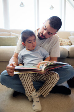 Father teaching son while reading picture book to him at home