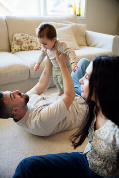 Father lying down on carpet while playing with son in living room at home