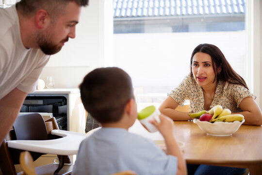 Mother talking with boy having breakfast at home