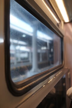 Interior view of a train passenger car with a window looking out at a station platform