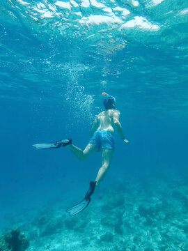 A man snorkeling above a coral reef in clear ocean water