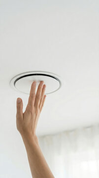 Woman hand touching ceiling air conditioner vent. Technician installing or adjusting indoor climate control system. Modern ventilation equipment, building service, house maintenance.