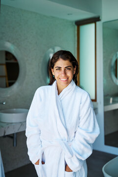 A smiling white woman enjoys relaxation in a modern bathroom