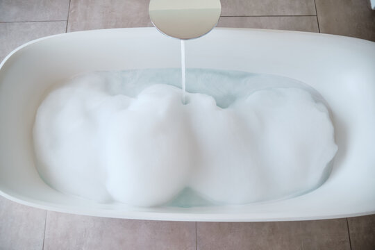 A bathtub filling with foam and water in a modern bathroom
