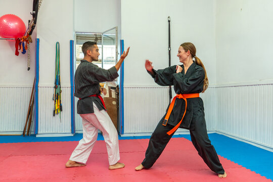 Man and woman practicing hapkido combat skills, wearing uniforms and colored belts during a training session in a dojang