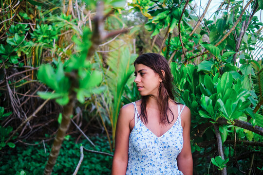 A white woman stands surrounded by tropical greenery