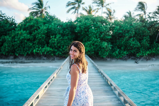 A young white woman walks and smiles on a pier