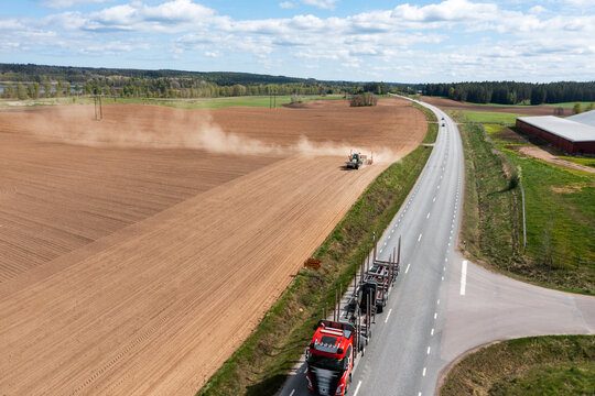 Drone point of view of tractor plowing agricultural field under cloudy sky