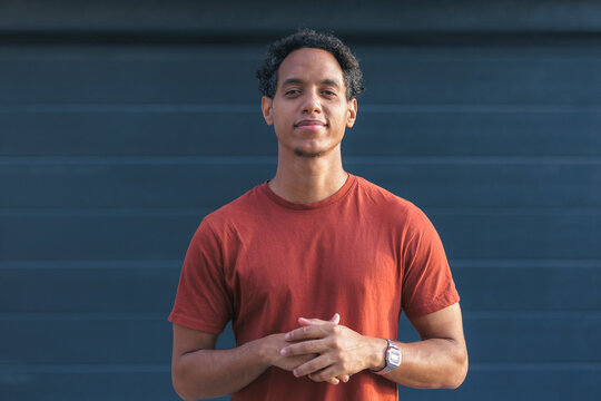 young man of mixed race stands outside in a relaxed way