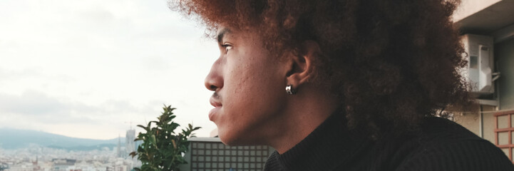 Fototapeta premium Close-up of young guy is standing on the balcony looking at the city . Panoramic