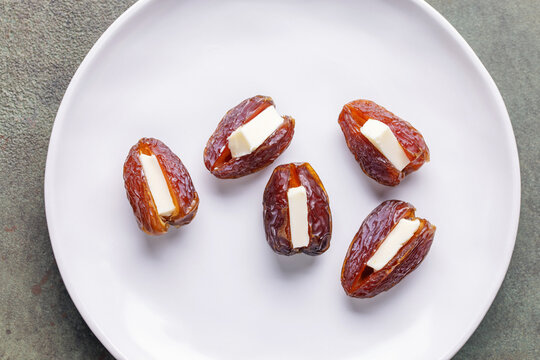 Dates Medjool stuffed with butter on white plate. Top view