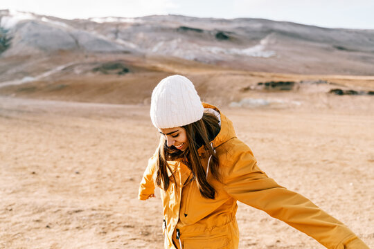 A white woman in a yellow jacket stretches her arms in an Iceland