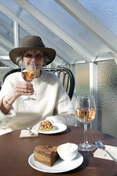Portrait of smiling senior woman holding wineglass while sitting at restaurant