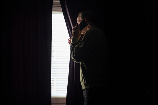 Side view of senior man talking on smartphone near window